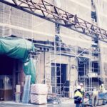 a group of people standing outside of a building under construction