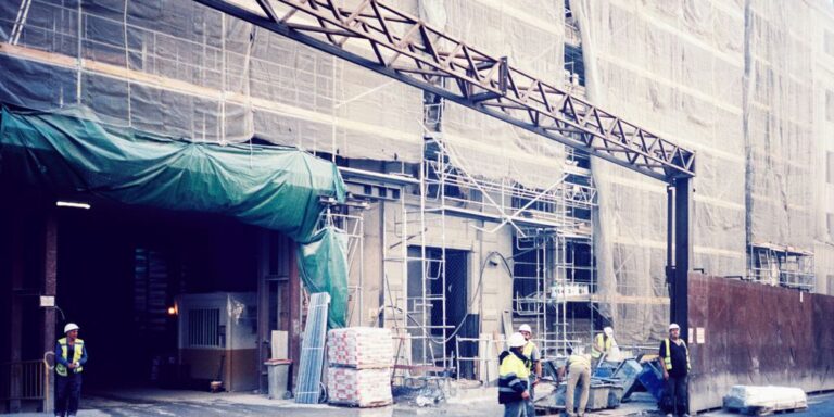a group of people standing outside of a building under construction